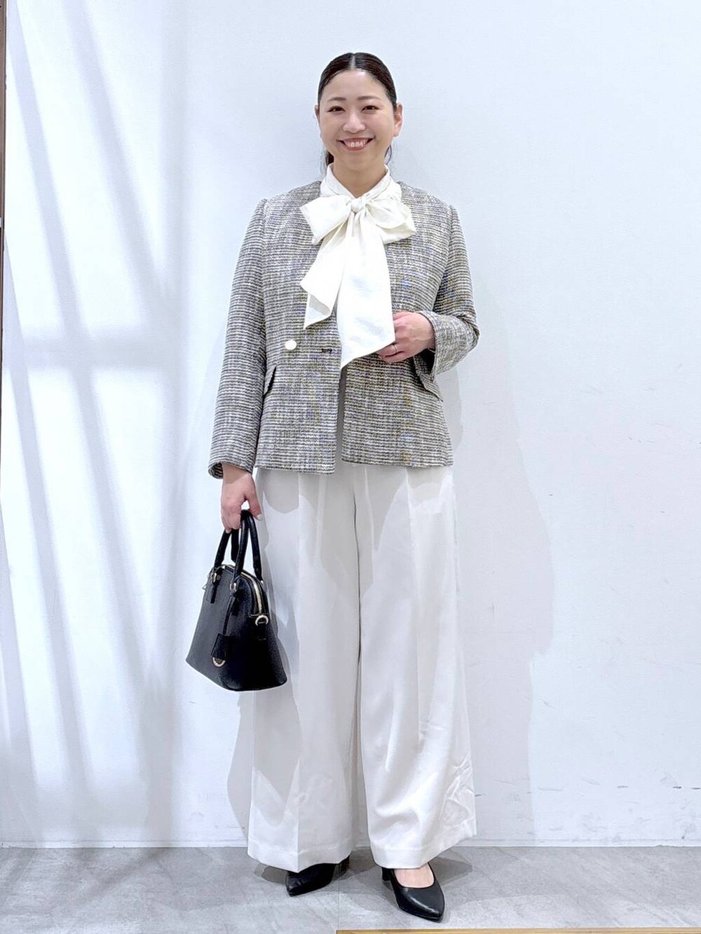 ブラック系のハンドバッグ、ブラック系のノーカラージャケット、ホワイト系のシャツ/ブラウスを着用したレディースの冬コーディネートの2枚目の写真