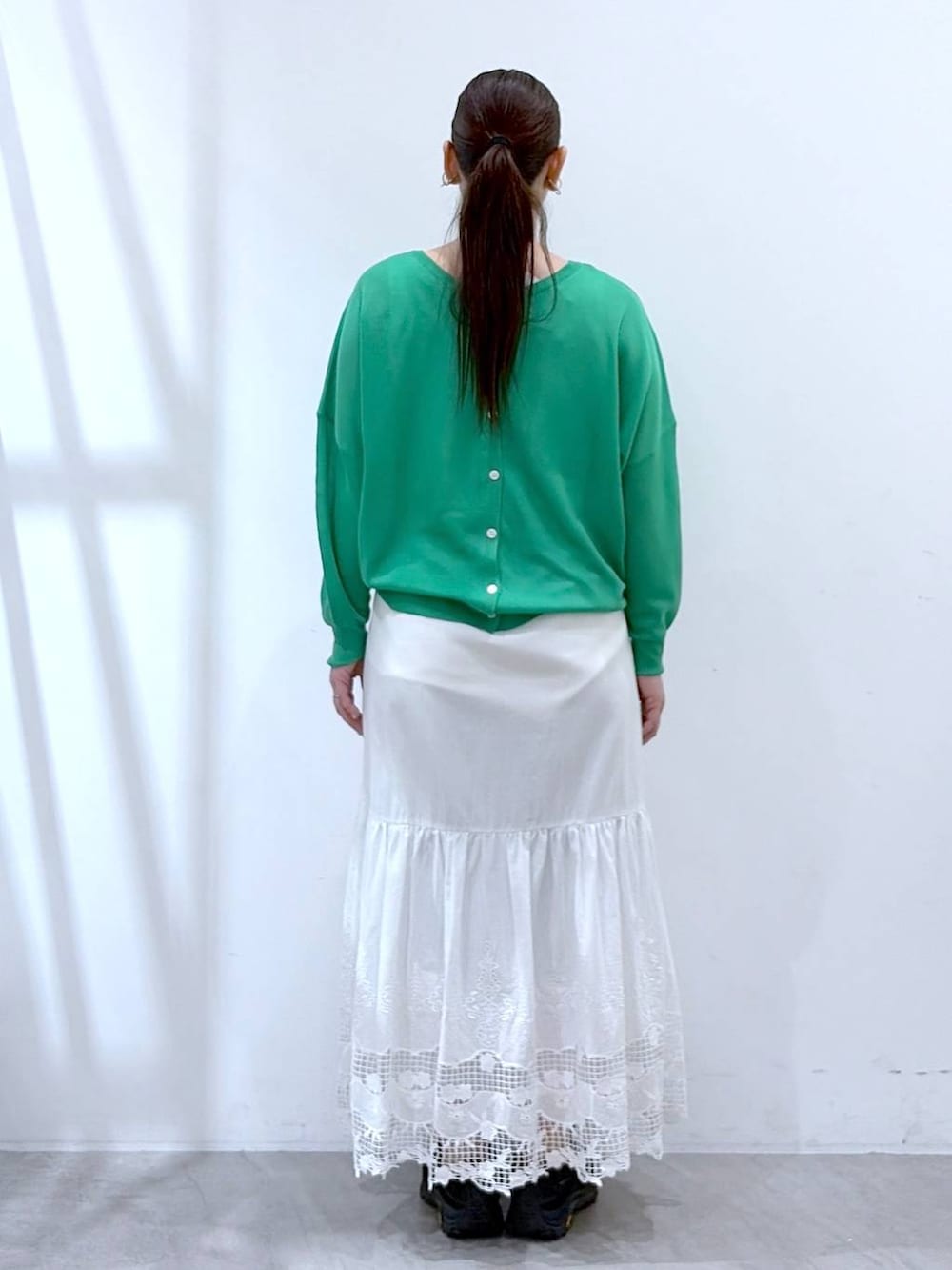 ブラック系のトートバッグ、ホワイト系のスカート、グリーン系のカーディガン/ボレロを着用したレディースの春コーディネートの4枚目の写真