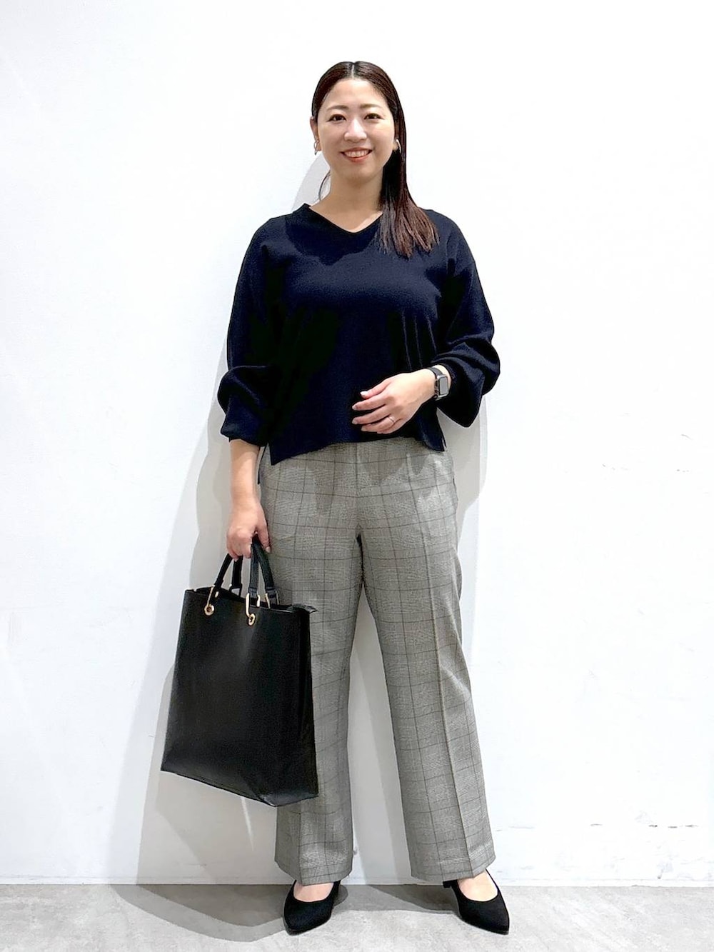 ブラック系のトートバッグ、ブルー系のニット/セーター、ブラック系のパンプスを着用したレディースの冬コーディネートの2枚目の写真