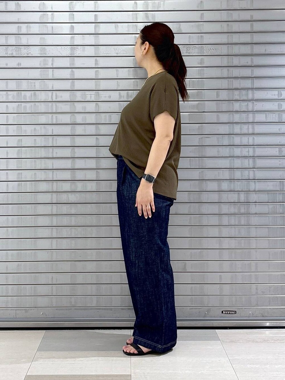 ブルー系のデニムパンツ、ブラック系のハンドバッグ、グリーン系のTシャツ/カットソーを着用したレディースの春コーディネートの3枚目の写真