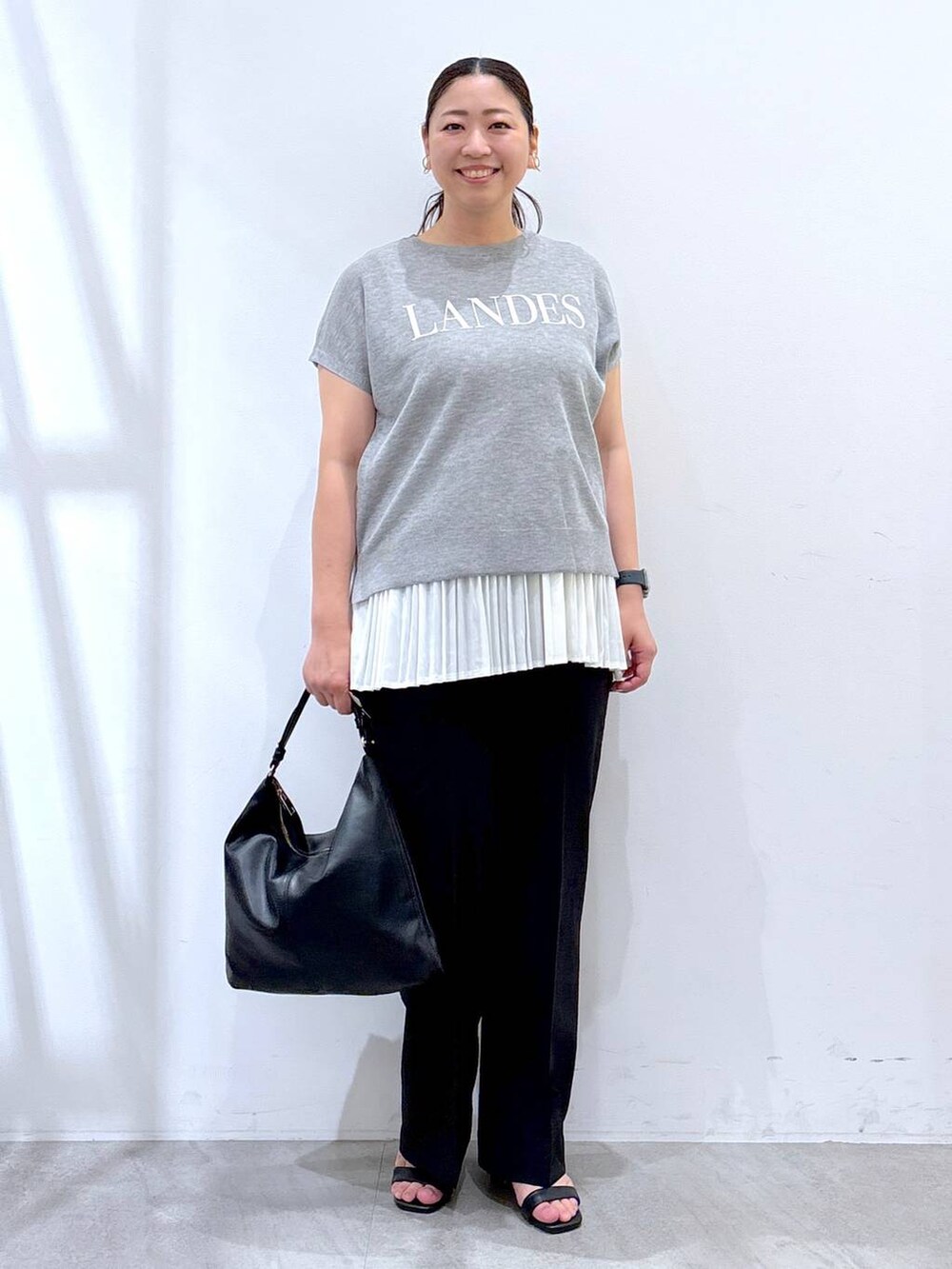 ホワイト系のタンクトップ、ブラック系のハンドバッグ、ブラック系のその他パンツを着用したレディースの夏コーディネートの2枚目の写真