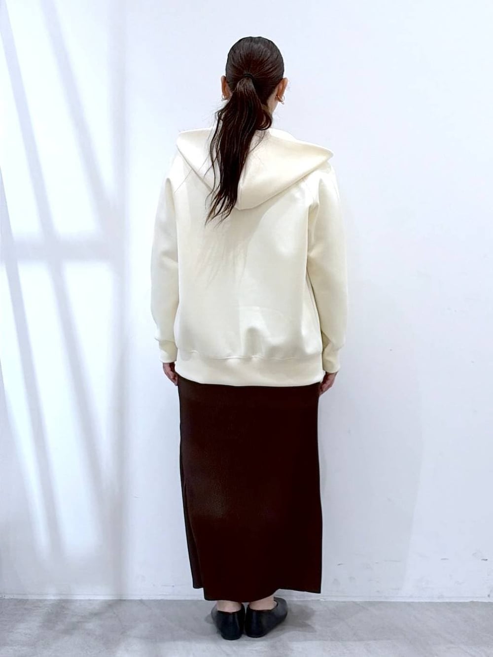 ホワイト系のパーカー、ブラウン系のスカート、ブラック系のショルダーバッグを着用したレディースの春コーディネートの4枚目の写真