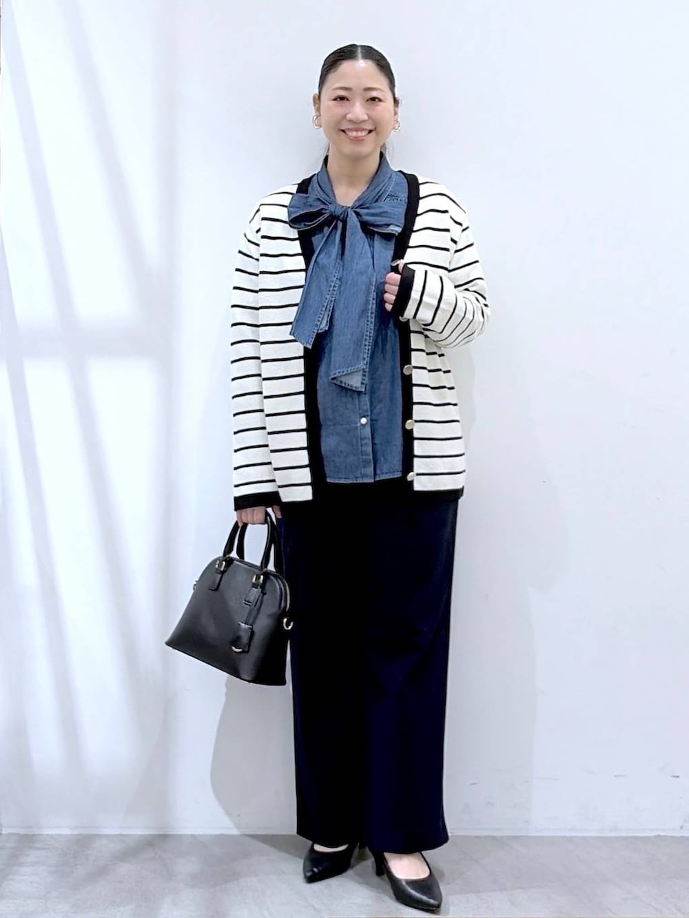 ブラック系のハンドバッグ、ブルー系のその他パンツ、ホワイト系のカーディガン/ボレロを着用したレディースの春コーディネートの2枚目の写真