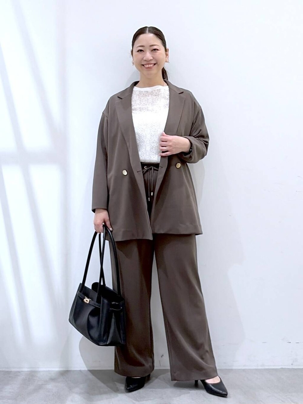 ブラウン系のその他パンツ、ブラック系のハンドバッグ、ブラウン系のテーラードジャケットを着用したレディースの春コーディネートの2枚目の写真