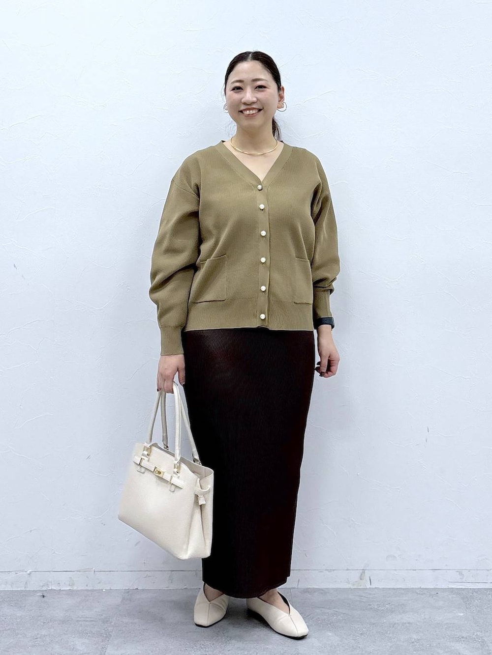 ホワイト系のパンプス、ホワイト系のハンドバッグ、イエロー系のカーディガン/ボレロを着用したレディースの冬コーディネートの2枚目の写真