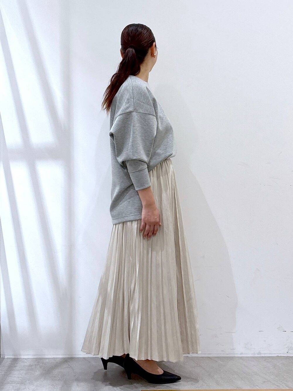 ブラック系のパンプス、グレー系のTシャツ/カットソー、ベージュ系のスカートを着用したレディースの秋コーディネートの4枚目の写真