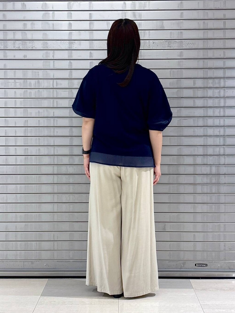 ブラック系のハンドバッグ、ブルー系のTシャツ/カットソー、ベージュ系のその他パンツを着用したレディースの春コーディネートの4枚目の写真