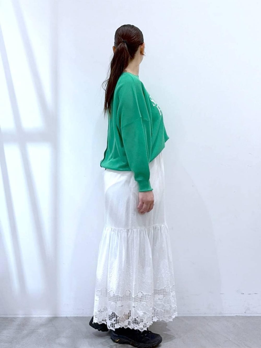 ブラック系のトートバッグ、ホワイト系のスカート、グリーン系のカーディガン/ボレロを着用したレディースの春コーディネートの5枚目の写真