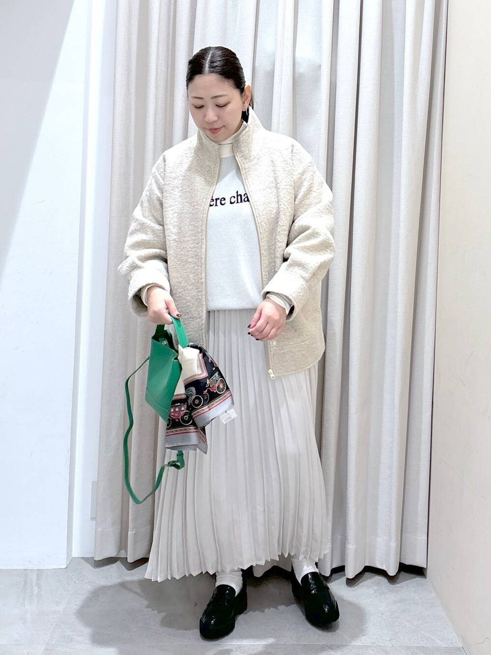 ブラック系のパンプス、ホワイト系のニット/セーター、ホワイト系のスカートを着用したレディースの秋コーディネートの2枚目の写真