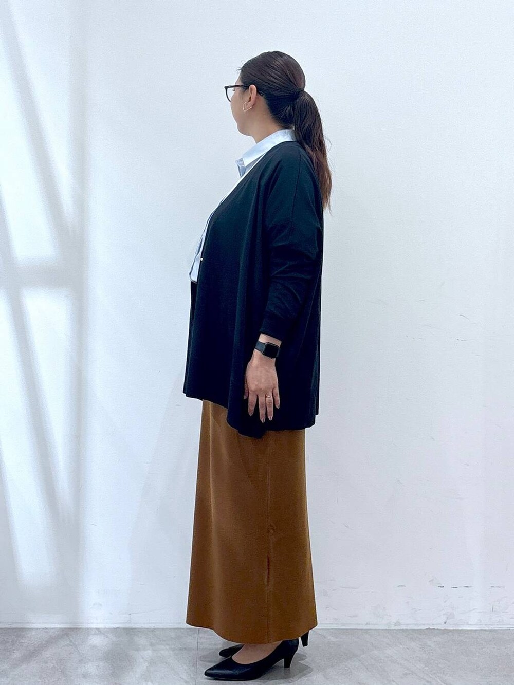 ブラック系のパンプス、ブラック系のカーディガン/ボレロ、イエロー系のスカートを着用したレディースの秋コーディネートの3枚目の写真