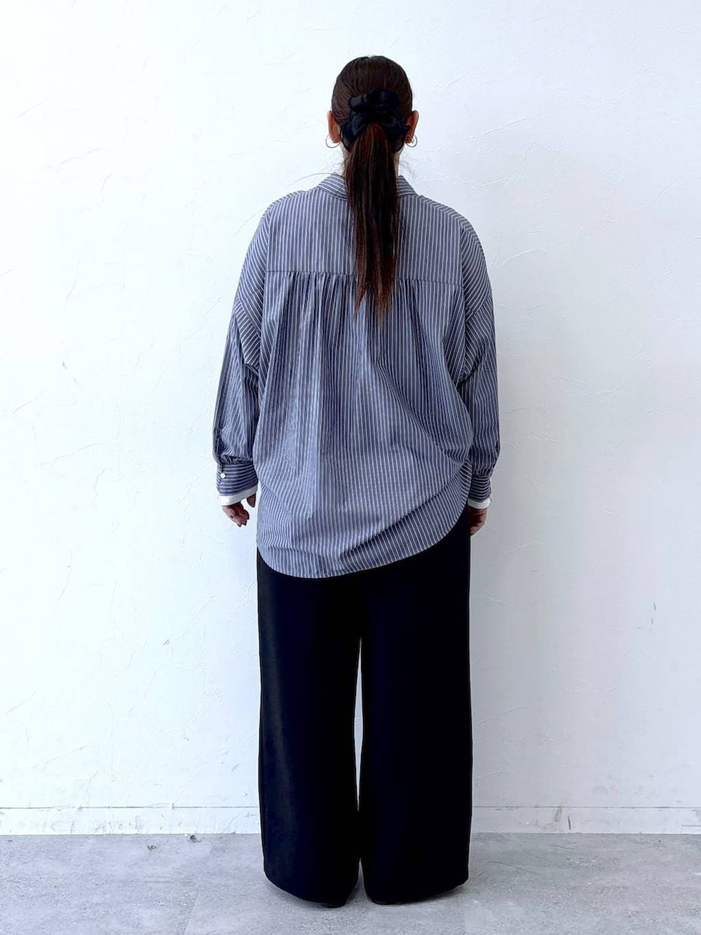 ブラック系のハンドバッグ、ブラック系のパンプス、ブルー系のシャツ/ブラウスを着用したレディースの冬コーディネートの4枚目の写真