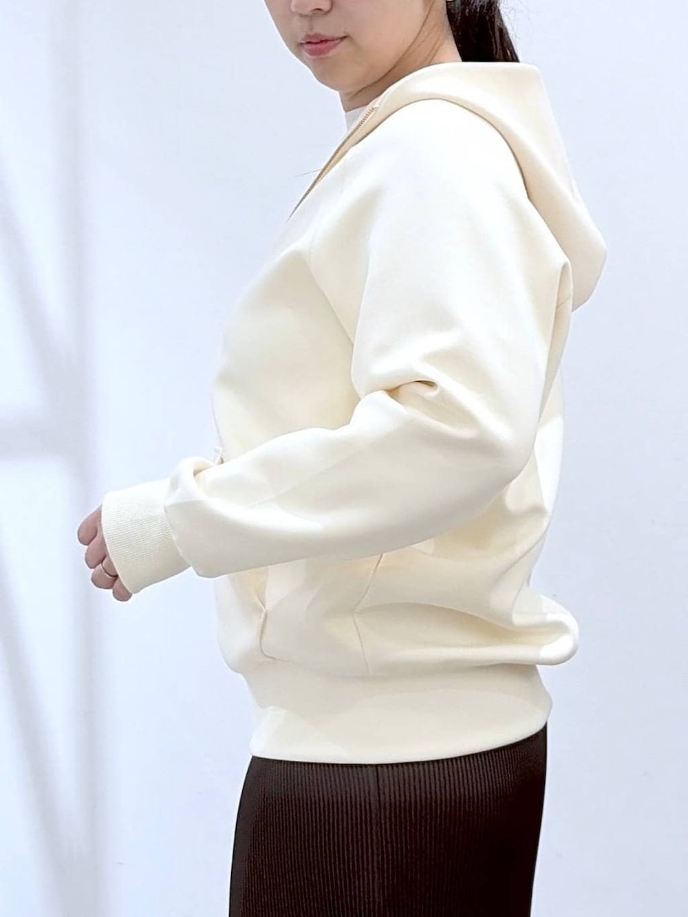 ホワイト系のパーカー、ブラウン系のスカート、ブラック系のショルダーバッグを着用したレディースの春コーディネートの8枚目の写真