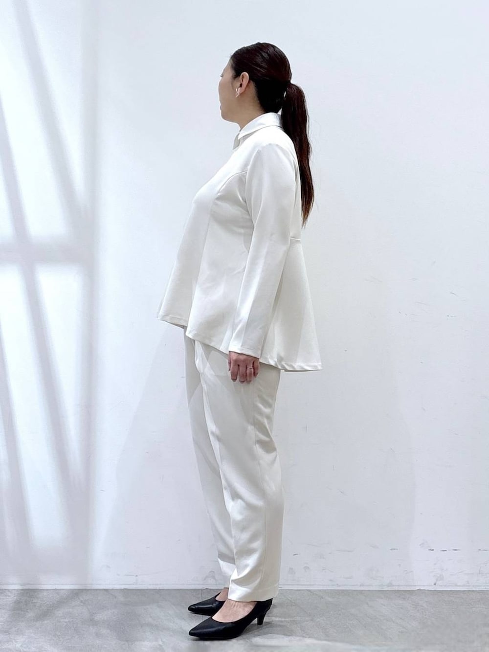 ブラック系のハンドバッグ、ホワイト系のシャツ/ブラウス、ホワイト系のスラックスを着用したレディースの春コーディネートの3枚目の写真