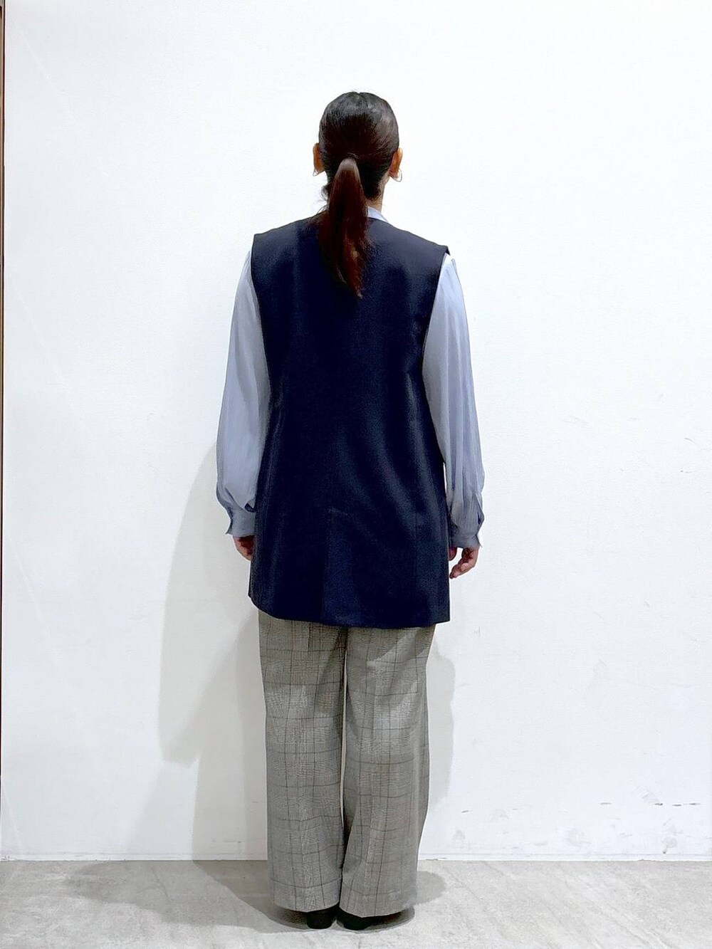 ブルー系のベスト、ブラック系のハンドバッグ、ブルー系のシャツ/ブラウスを着用したレディースの秋コーディネートの4枚目の写真