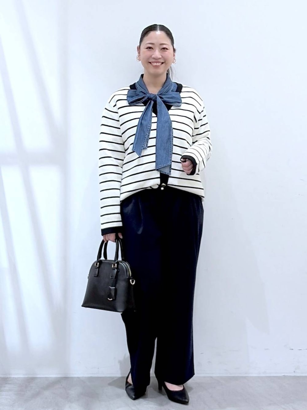 ブラック系のハンドバッグ、ブルー系のその他パンツ、ホワイト系のカーディガン/ボレロを着用したレディースの春コーディネートの3枚目の写真
