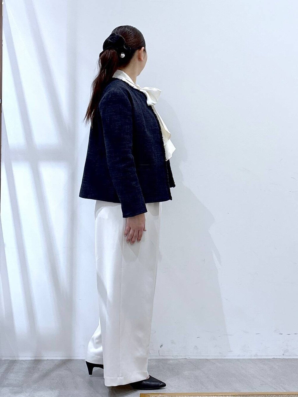 ブルー系のノーカラージャケット、ホワイト系のスラックス、ホワイト系のシャツ/ブラウスを着用したレディースの冬コーディネートの5枚目の写真