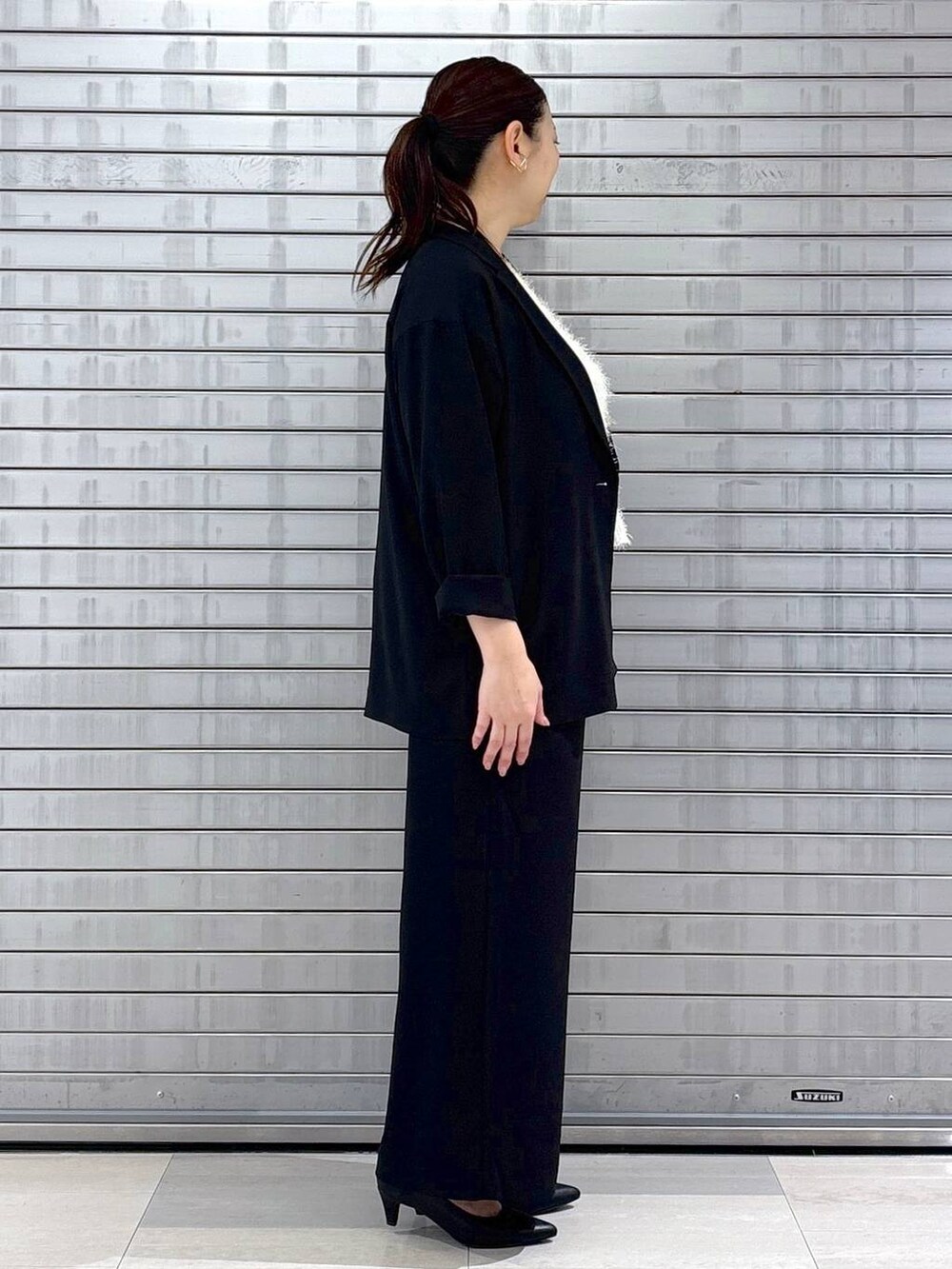 ブラック系のハンドバッグ、ホワイト系のベストを着用したレディースの春コーディネートの5枚目の写真