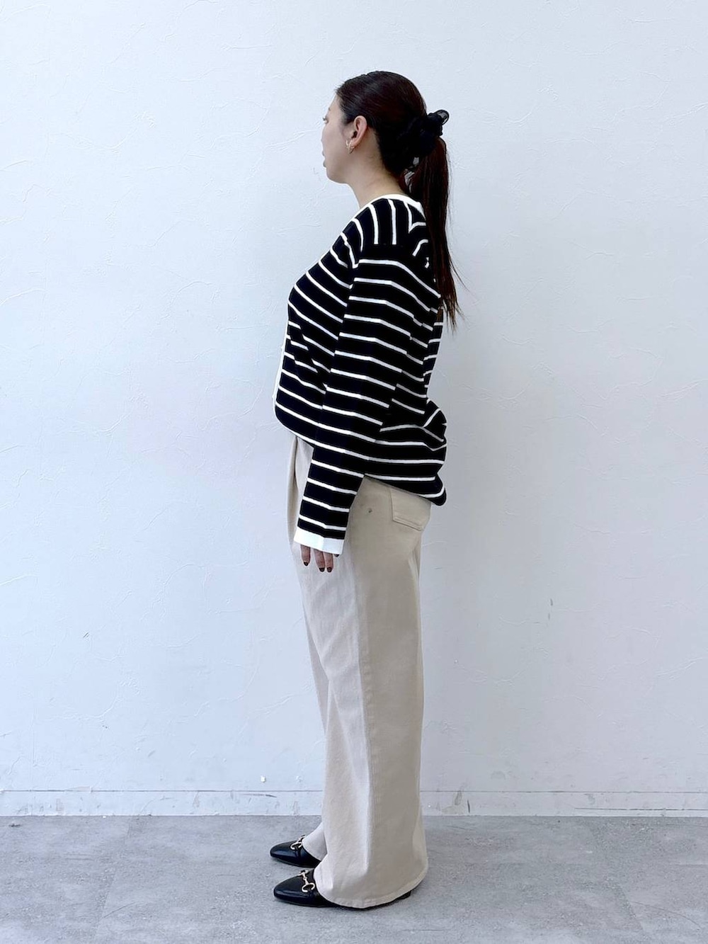 ブラック系のハンドバッグ、ベージュ系のデニムパンツ、ブラック系のカーディガン/ボレロを着用したレディースの冬コーディネートの3枚目の写真