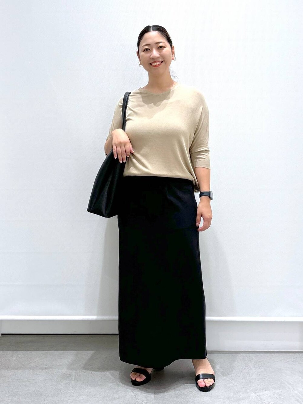 ブラック系のサンダル、ベージュ系のニット/セーター、ブラック系のスカートを着用したレディースの秋コーディネートの2枚目の写真