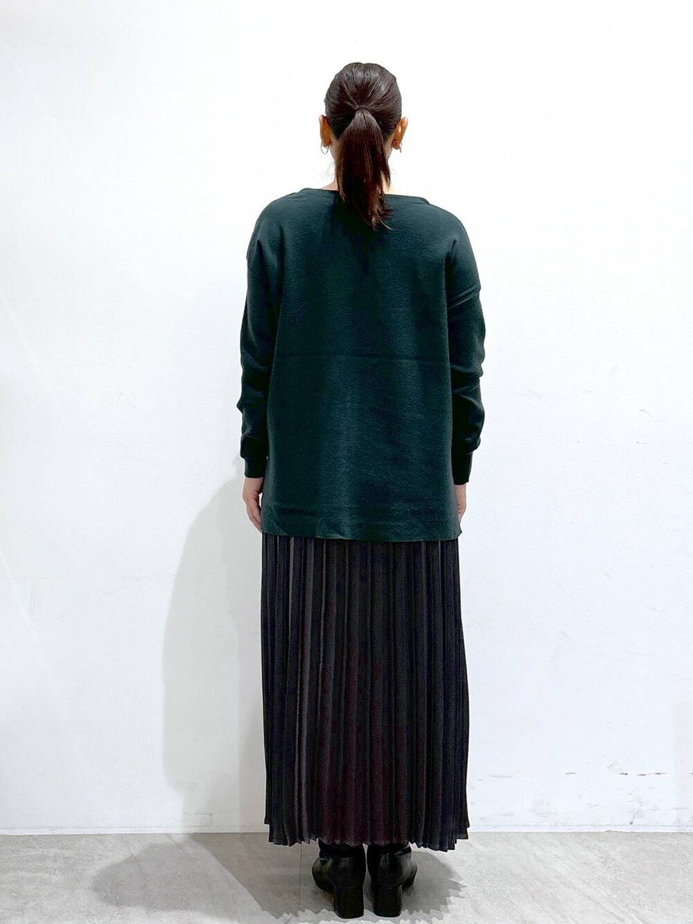 ブラック系のブーツ、グリーン系のニット/セーター、グレー系のスカートを着用したレディースの秋コーディネートの4枚目の写真