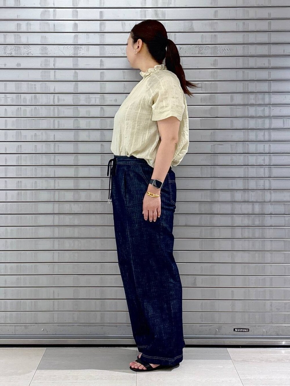 ブルー系のデニムパンツ、ブラック系のハンドバッグ、ホワイト系のシャツ/ブラウスを着用したレディースの夏コーディネートの3枚目の写真