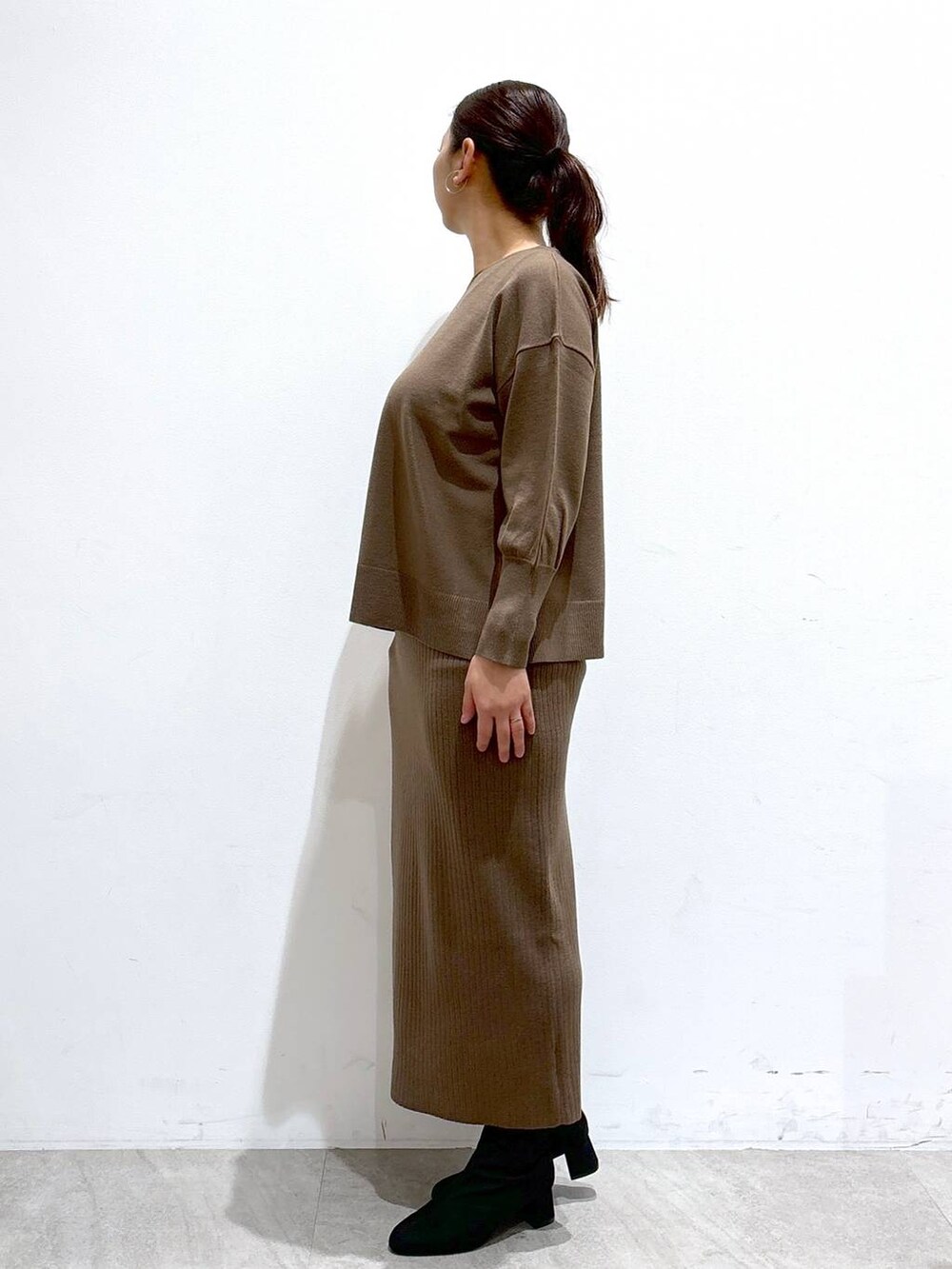 グレー系のブーツ、ブラック系のハンドバッグ、ホワイト系のその他アウターを着用したレディースの冬コーディネートの3枚目の写真