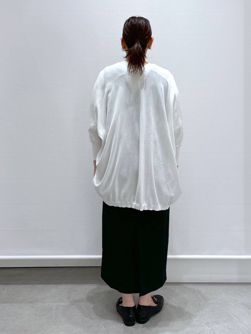 イエロー系のシャツ/ブラウス、ホワイト系のカーディガン/ボレロ、ブラック系のジャンパースカートを着用したレディースの春コーディネートの4枚目の写真