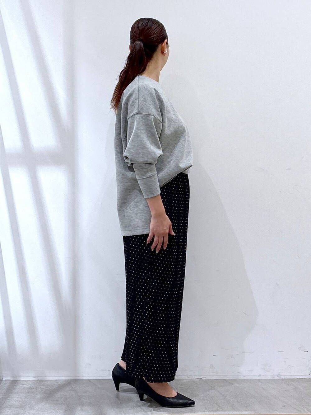 ブラック系のパンプス、グレー系のTシャツ/カットソー、ブラック系のスカートを着用したレディースの秋コーディネートの4枚目の写真