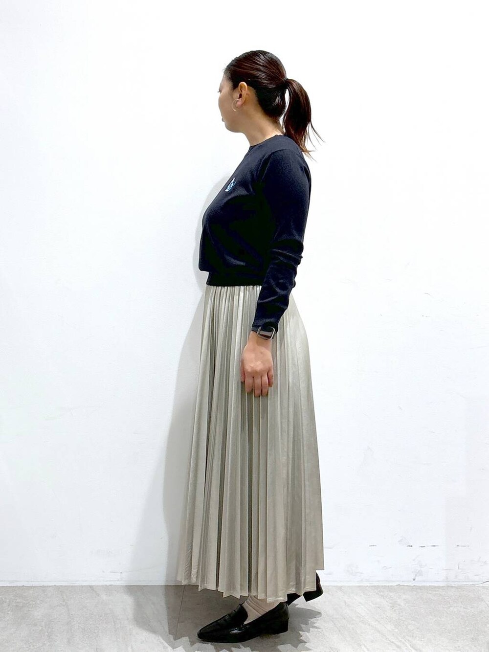 シルバー系のスカート、ブラック系のブーツ、ブルー系のニット/セーターを着用したレディースの秋コーディネートの3枚目の写真