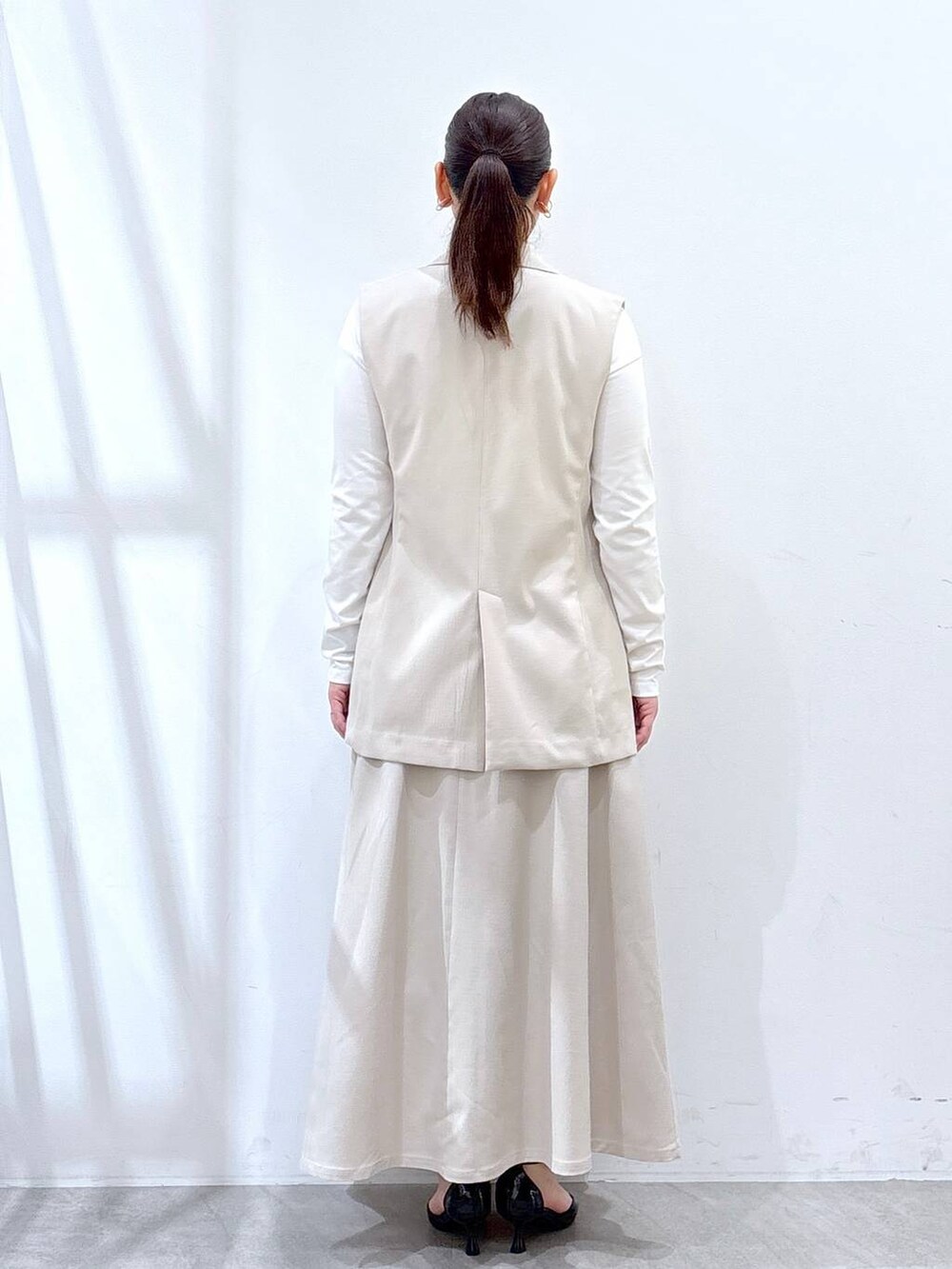 ベージュ系のスカート、ベージュ系のベスト、ホワイト系のTシャツ/カットソーを着用したレディースの春コーディネートの4枚目の写真