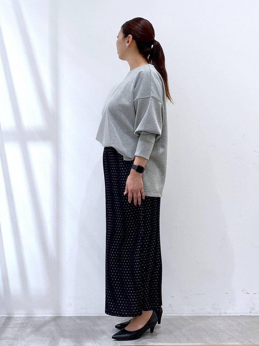 ブラック系のパンプス、グレー系のTシャツ/カットソー、ブラック系のスカートを着用したレディースの秋コーディネートの2枚目の写真