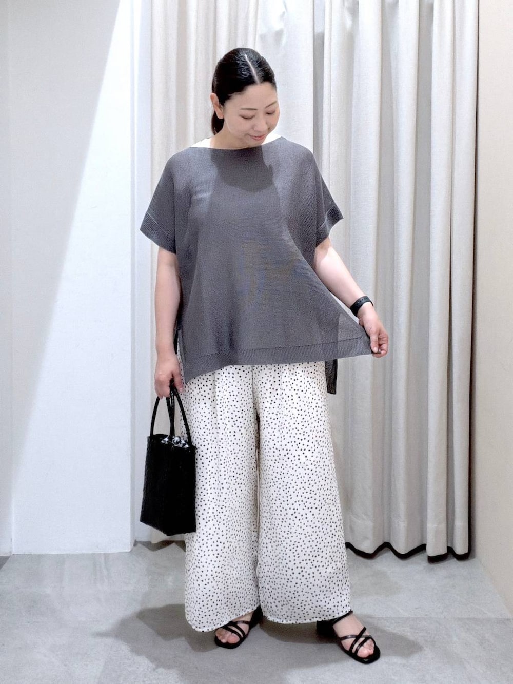 ブラック系のサンダル、ホワイト系のその他パンツ、ブラック系のかごバッグを着用したレディースの夏コーディネートの2枚目の写真