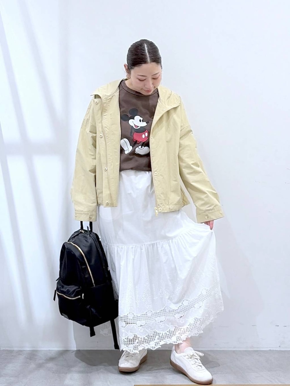 ブラウン系のTシャツ/カットソー、ブラック系のバックパック/リュック、ホワイト系のスカートを着用したレディースの春コーディネートの2枚目の写真