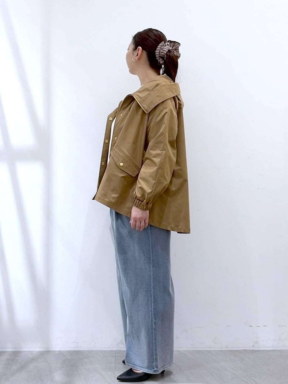 ブラック系のトートバッグ、ホワイト系のニット/セーター、ブルー系のデニムパンツを着用したレディースの春コーディネートの3枚目の写真