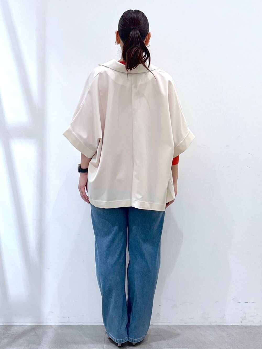 ベージュ系のパンプス、ブルー系のデニムパンツ、オレンジ系のニット/セーターを着用したレディースの春コーディネートの4枚目の写真
