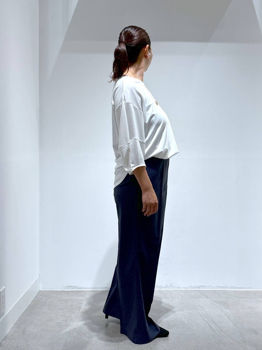 ブラック系のトートバッグ、ブラック系のパンプス、ブルー系のデニムパンツを着用したレディースの秋コーディネートの4枚目の写真