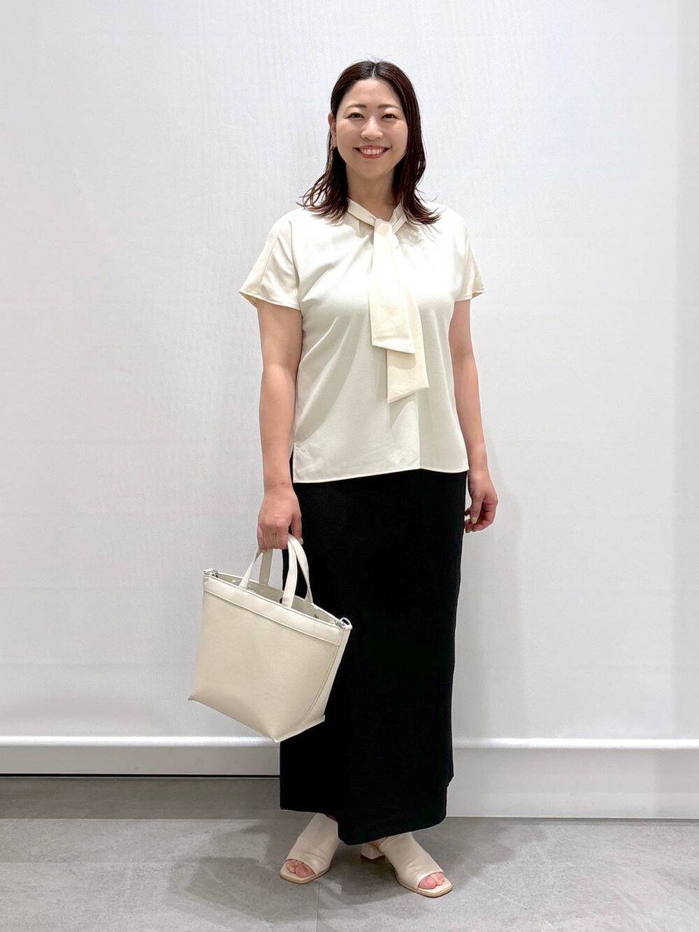 ホワイト系のシャツ/ブラウス、ホワイト系のサンダル、ブラック系のスカートを着用したレディースの夏コーディネートの2枚目の写真