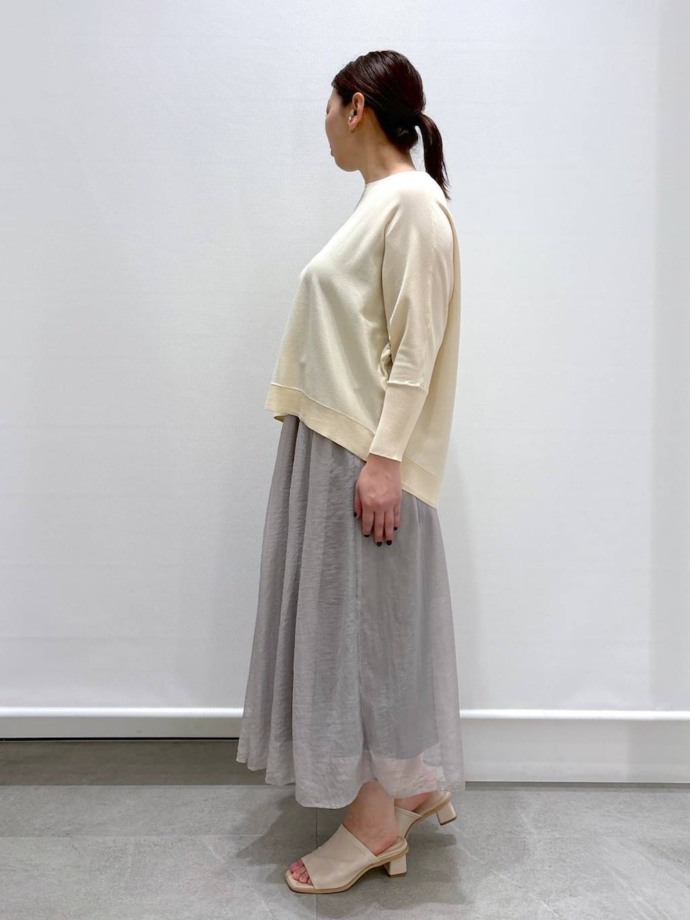 グレー系のスカート、ホワイト系のニット/セーター、ホワイト系のショルダーバッグを着用したレディースの春コーディネートの3枚目の写真