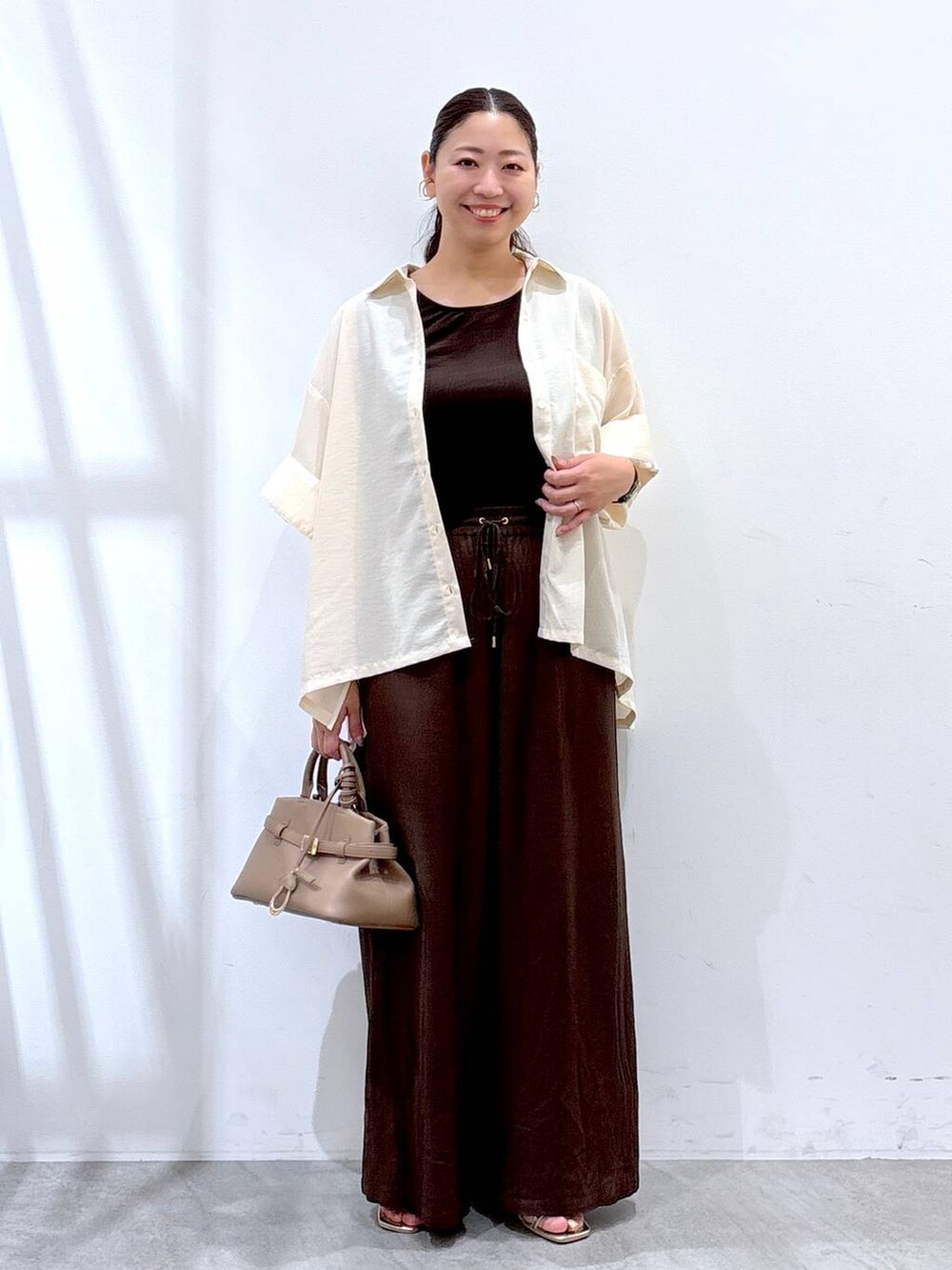 ブラウン系のその他パンツ、ゴールド系のサンダル、ホワイト系のシャツ/ブラウスを着用したレディースの夏コーディネートの2枚目の写真