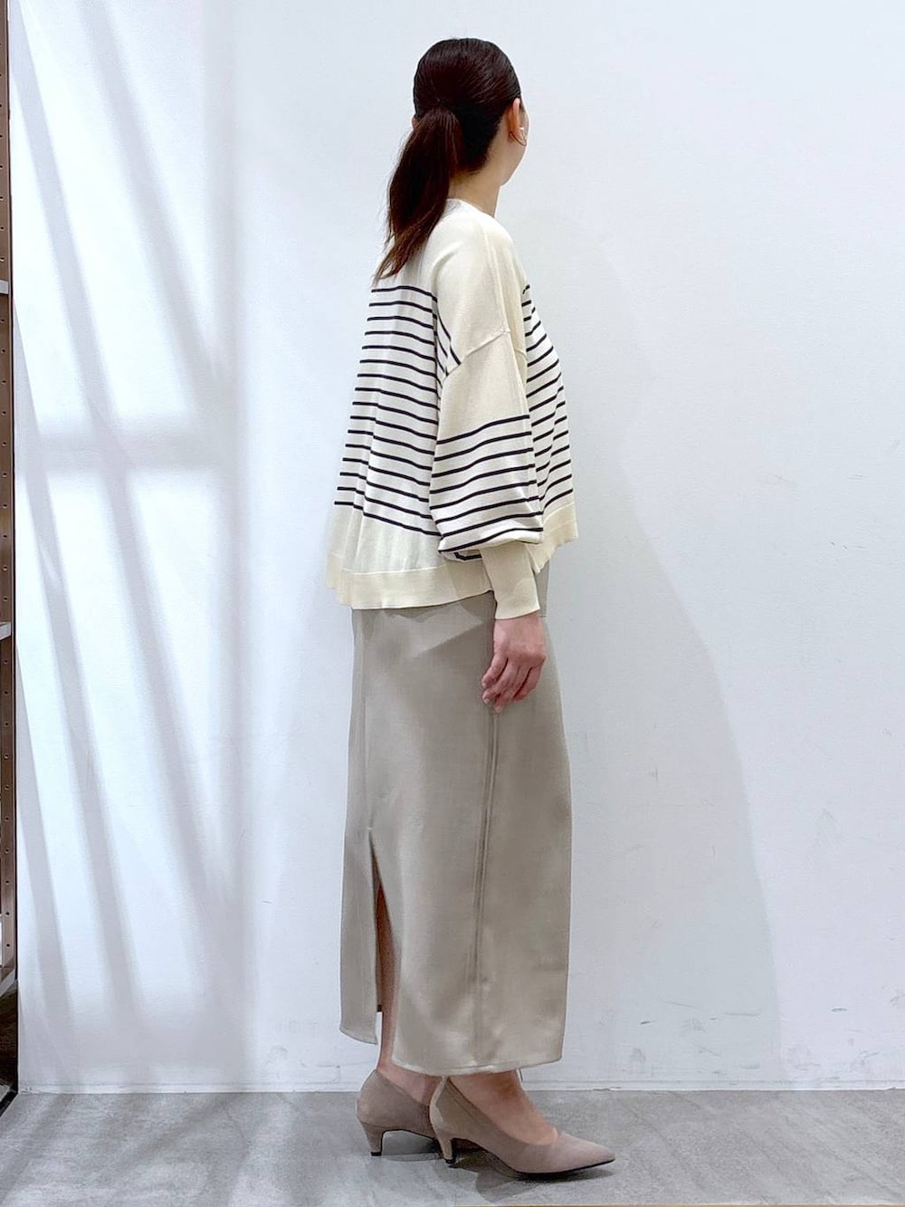 ベージュ系のパンプス、ホワイト系のスカート、ブルー系のニット/セーターを着用したレディースの春コーディネートの5枚目の写真