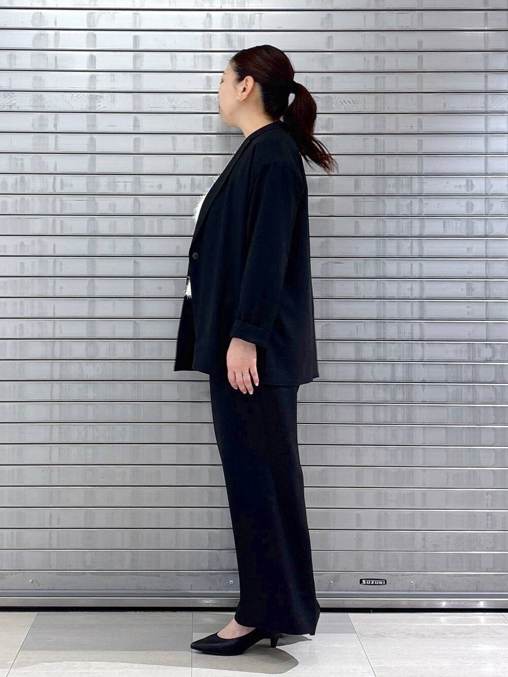 ブラック系のハンドバッグ、ホワイト系のベストを着用したレディースの春コーディネートの3枚目の写真