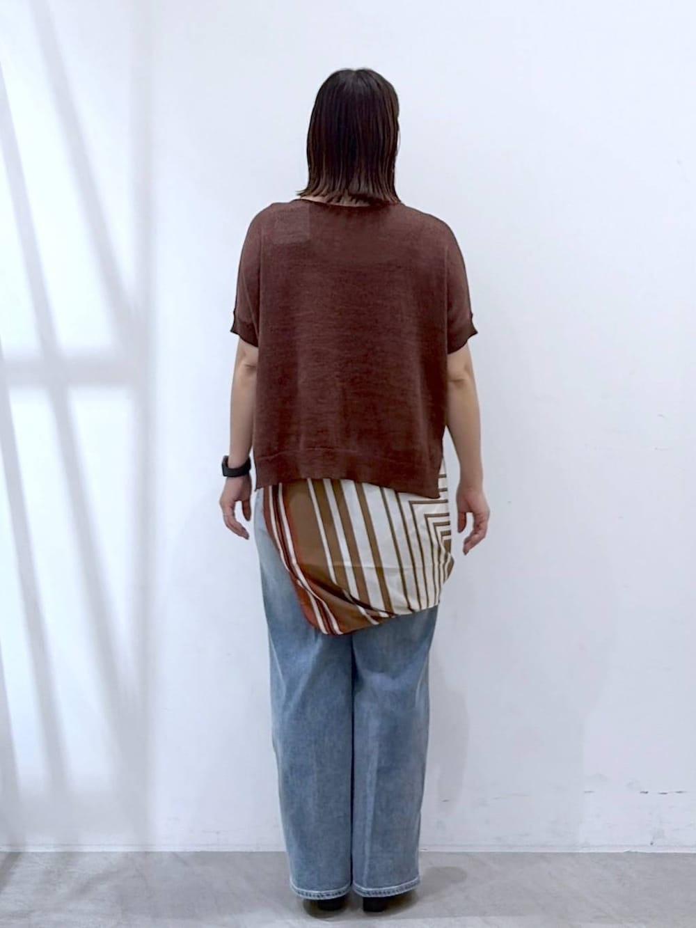 ブラック系のサンダル、ブルー系のデニムパンツ、ブラウン系のストール/ショールを着用したレディースの秋コーディネートの4枚目の写真
