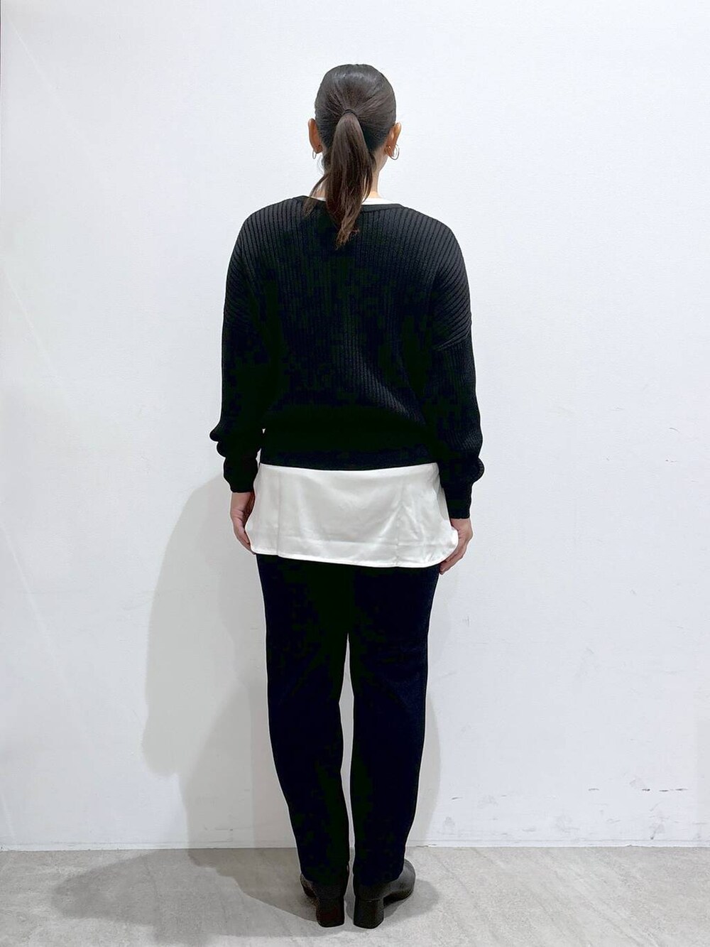 ブラック系のカーディガン/ボレロ、ブラック系のハンドバッグ、ブラック系のブーツを着用したレディースの秋コーディネートの4枚目の写真