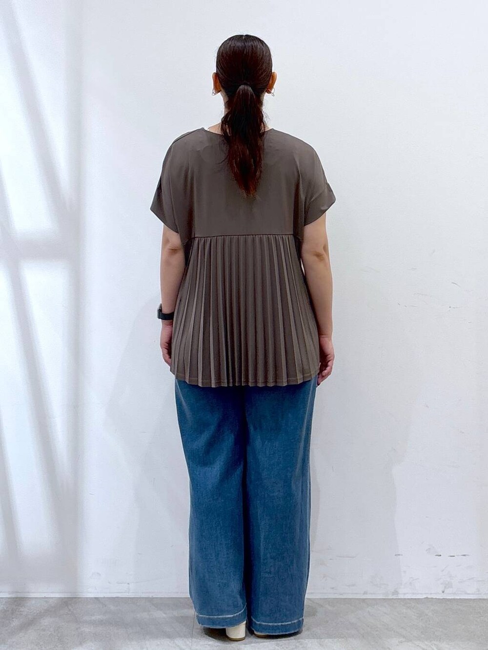 グリーン系のTシャツ/カットソー、シルバー系のトートバッグ、ブルー系のデニムパンツを着用したレディースの夏コーディネートの4枚目の写真