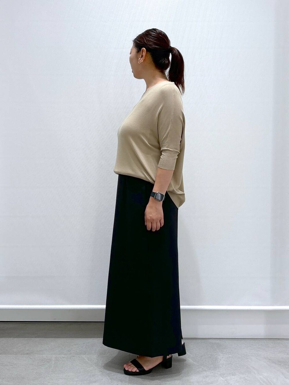 ブラック系のサンダル、ベージュ系のニット/セーター、ブラック系のスカートを着用したレディースの秋コーディネートの3枚目の写真