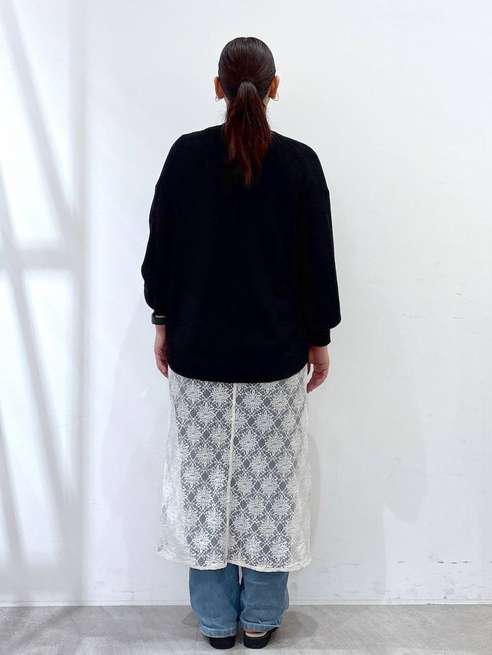 ホワイト系のワンピース、ホワイト系のハンドバッグ、ブルー系のデニムパンツを着用したレディースの春コーディネートの4枚目の写真