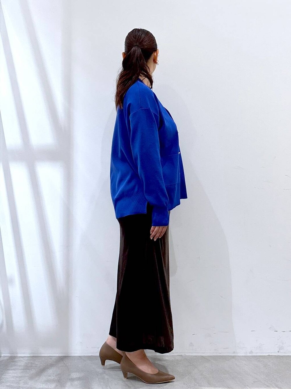 ブラウン系のパンプス、ブルー系のカーディガン/ボレロ、ブラック系のタンクトップを着用したレディースの秋コーディネートの5枚目の写真