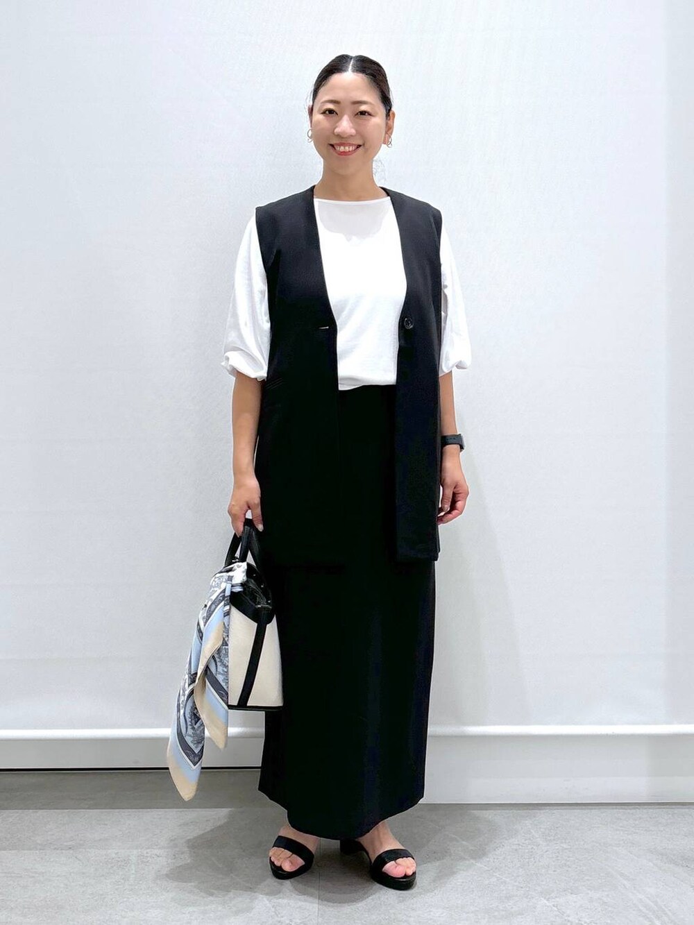 ブラック系のトートバッグ、ブラック系のサンダル、ブラック系のスカートを着用したレディースの秋コーディネートの2枚目の写真