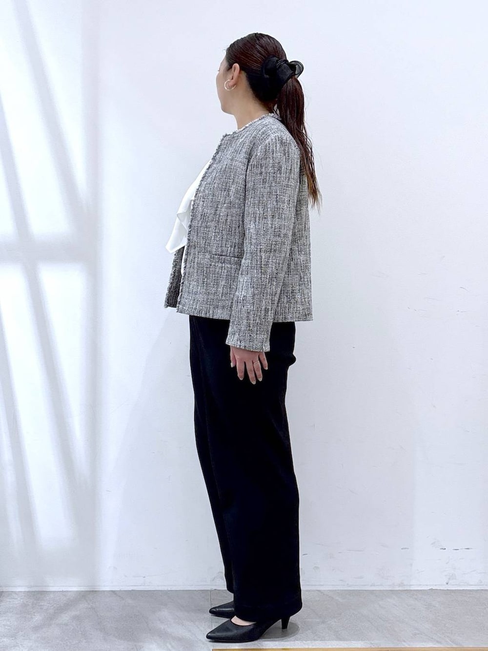 ブラック系のハンドバッグ、ブラック系のその他パンツ、ブラック系のノーカラージャケットを着用したレディースの冬コーディネートの3枚目の写真