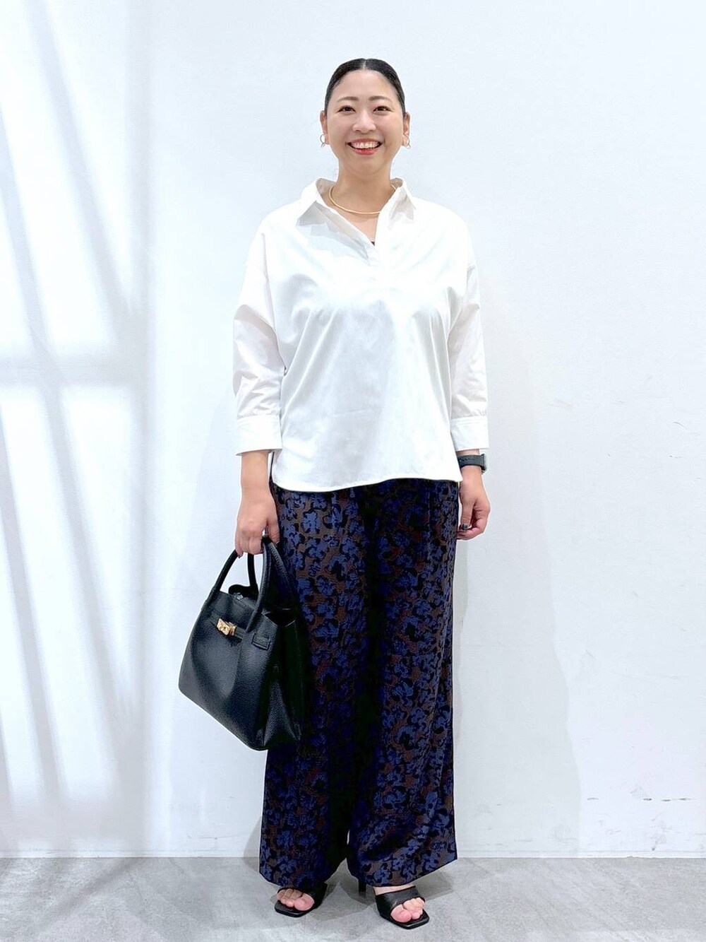 ブラック系のハンドバッグ、ブラウン系のその他パンツ、ホワイト系のシャツ/ブラウスを着用したレディースの秋コーディネートの2枚目の写真